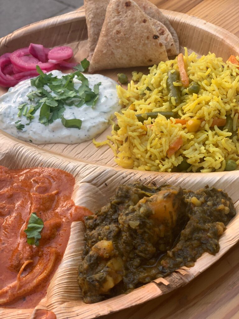 A thali filled with Indian dishes including saag, rice and butter chicken